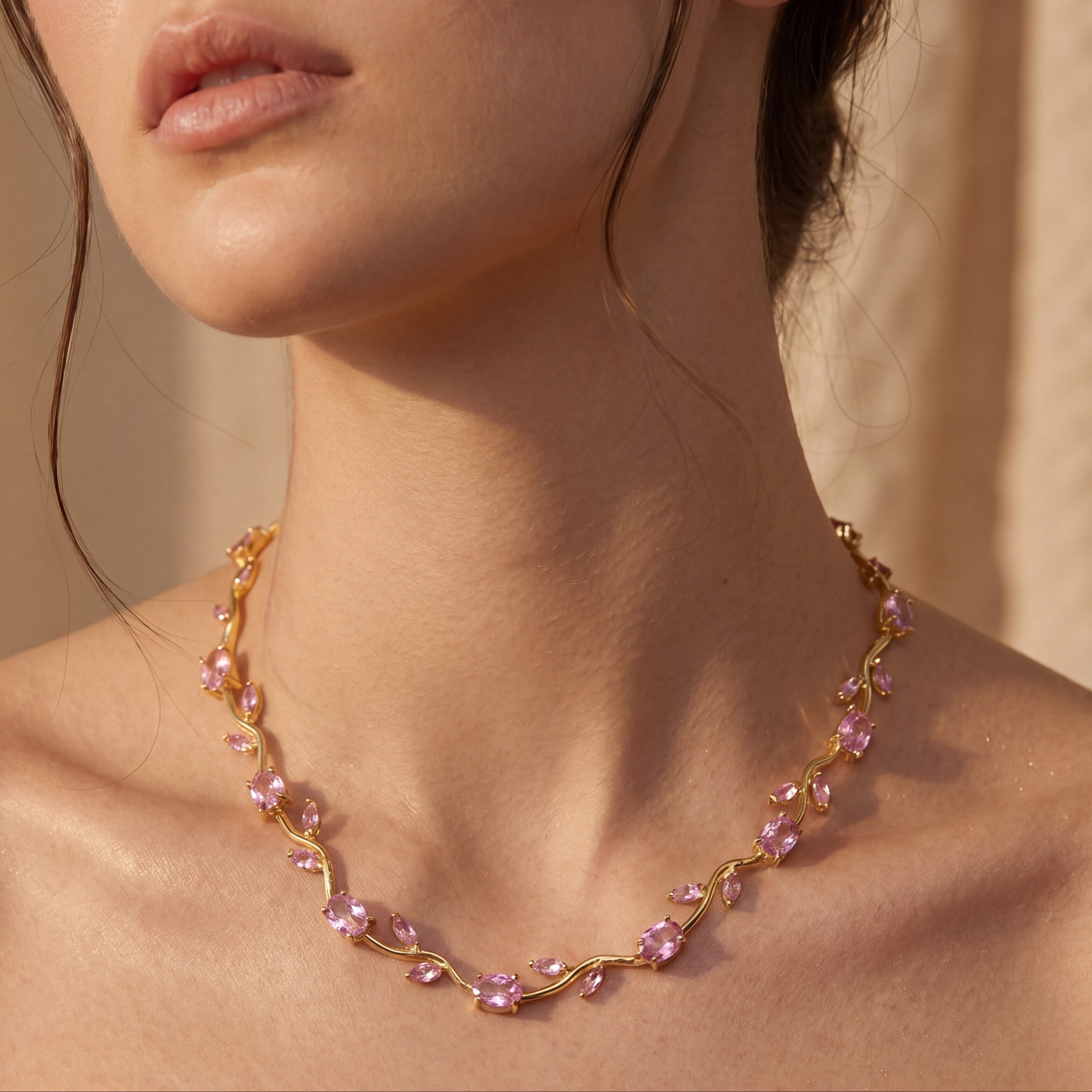 Woman wearing a delicate necklace with pink beads against a neutral background